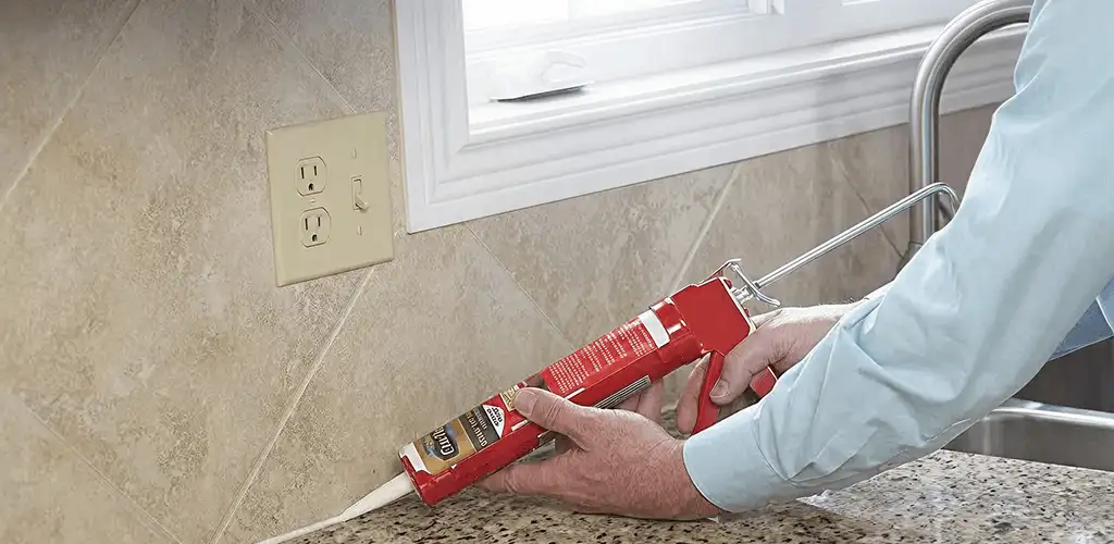 Handyman applying caulk along a kitchen backsplash and countertop seam in Duluth, MN