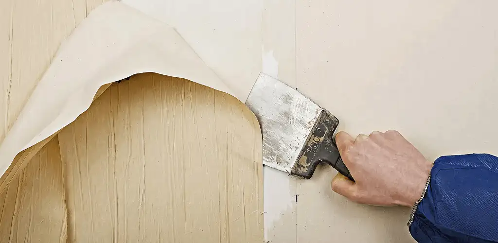 Handyman removing wallpaper with a scraper for wall preparation in Duluth, MN