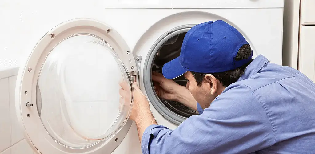 Washing machine repair handyman inspecting a front-load washer drum in Duluth, MN