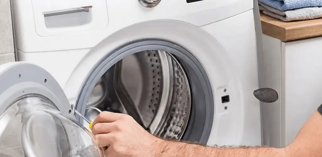 Handyman repairing a front-load washing machine and inspecting the drum in Duluth, MN